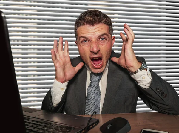 Joven estresado y abrumado hombre de negocios en traje y corbata desesperado trabajando en escritorio de la computadora portátil de oficina gritando loco sufrimiento estrés problema —  Fotos de Stock