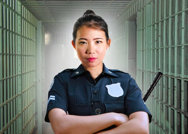 Joven seria y atractiva asiática coreana guardia mujer de pie en la celda en la penitenciaría estatal vistiendo uniforme de policía en el delito pena de prisión y aplicación de la ley — Foto de Stock