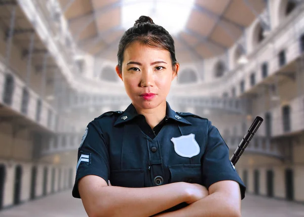 Młody poważny i atrakcyjny Azji amerykański gwardia kobieta stoi w stanowy więzienny sala mając policyjny mundur w przestępczości kara — Zdjęcie stockowe