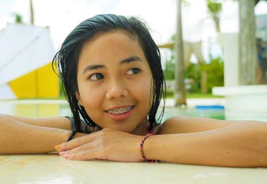 genç güzel ve tatlı Asya Endonezyalı genç kız tropikal tatil havuzunda yüzme açık hava portresi mutlu ve neşeli rahat tatil gezisi zevk gülümseyerek