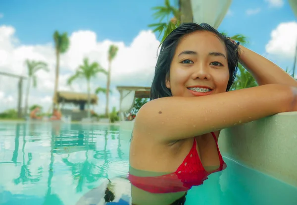 Portrait en plein air de jeune belle et douce asiatique adolescente indonésienne nageant à la piscine de villégiature tropicale souriant heureux et joyeux profiter de vacances détendues voyage — Photo