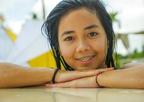 户外肖像年轻美丽和甜蜜的亚洲印尼少女游泳在热带度假胜地游泳池微笑快乐和欢快享受轻松的假期之旅 — 图库照片