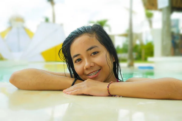 户外肖像年轻美丽和甜蜜的亚洲印尼少女游泳在热带度假胜地游泳池微笑快乐和欢快享受轻松的假期之旅 — 图库照片