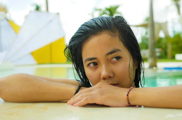 Outdoors portrait of young beautiful and sweet Asian Indonesian teenager girl swimming at tropical resort pool smiling happy and cheerful enjoying relaxed holidays trip — Stock Photo, Image