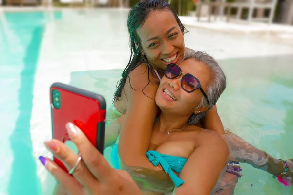 生活方式户外肖像亚洲女朋友享受暑假在热带海滩度假胜地游泳池拍摄自拍照片与手机玩 — 图库照片