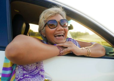 çekici ve mutlu orta yaşlı Asya Endonezyalı kadın 40s veya 50s gri saçlı ve güzel bir gülümseme penceresinden rahat bakarak gün batımı zevk arabasında oturan