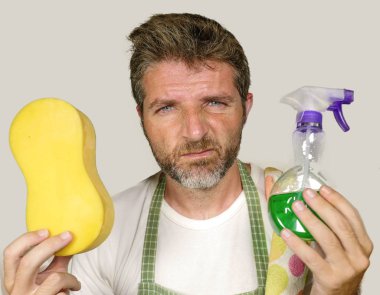 apron tutan adam sünger ve deterjan sprey duygu boğulmuş ve tembel ve rahatsız yüz temizlik ve yıkama ev ev işleri yapıyor sıkılmış