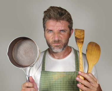 apron tutan kaşık ve tava da çekici mutsuz ve ezilmiş ev aşçı adam üzgün ve iç iş ve izole arka plan üzerinde pişirme görevi tembel duygu