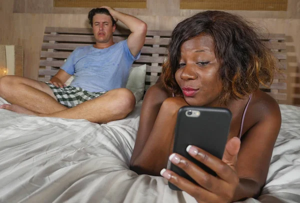 화가 와 의심스러운 백인 남자 또는 관계 부정 행위를 무시 휴대 전화를 사용하여 아름다운 검은 아프리카 미국의 아내 또는 여자 친구와 침대에 혼합 민족 커플 — 스톡 사진