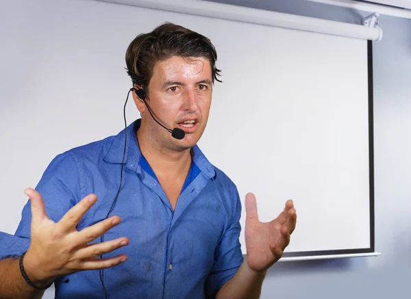 Hombre exitoso trabajando como orador motivacional y entrenador de gestión de negocios hablando con el público en la sala de conferencias usando micrófono de auriculares en la pantalla del proyector bg — Foto de Stock