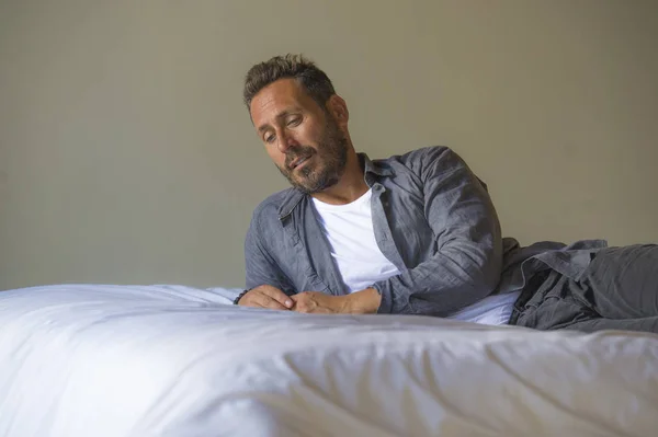 Retrato interior de 30 a 40 años hombre feliz y guapo en casa en camisa casual y jeans acostado en la cama relajado en casa pensamiento reflexivo y pensativo sobre algo — Foto de Stock