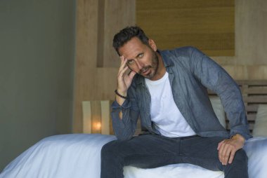 young attractive stressed and depressed man sitting on bed crying sad and frustrated suffering depression crisis fired from work or divorce problem feeling pain