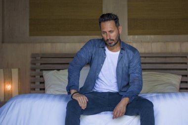 young attractive stressed and depressed man sitting on bed crying sad and frustrated suffering depression crisis fired from work or divorce problem feeling pain