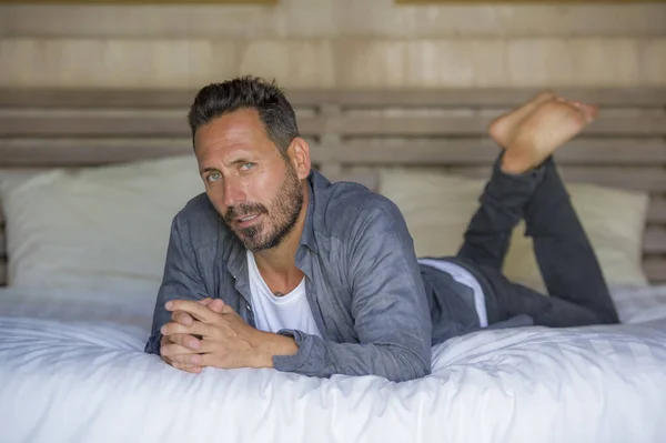 Retrato interior de 30 a 40 años hombre feliz y guapo en casa en camisa casual y jeans acostado en la cama relajado en casa sonriendo confiado y fresco sentirse positivo — Foto de Stock