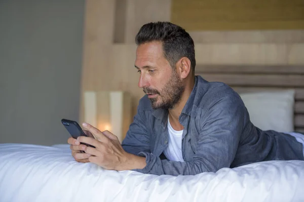 Giovane uomo bello e felice a casa utilizzando internet cellulare sul letto sorridente allegro e soddisfatto sentirsi rilassato incontri online o godendo di app di social media — Foto Stock