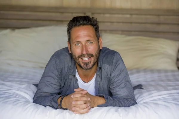 30s hombre feliz y guapo en casa en camisa casual y jeans acostado en la cama relajado en casa sonriendo confiado y feliz sentirse positivo en el concepto de estilo de vida masculino — Foto de Stock