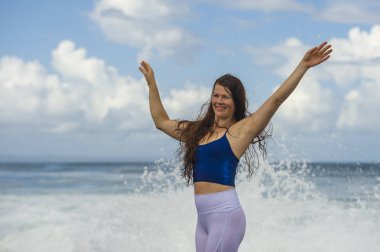 young happy and attractive red hair woman playing excited spreading arms feeling free and relaxed getting wet by sea waves splashing on her enjoying beach