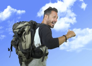mutlu ve çekici backpacker man30s veya 40s gülümseyen neşeli ve heyecanlı seyahat sırt çantası taşıma tatil seyahat ve macera mavi gökyüzünde izole zevk