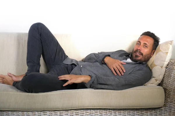 Estilo de vida casa retrato de joven atractivo y feliz hombre blanco con barba y camisa casual acostado relajado y acogedor en el sofá de la sala de estar sofá descansando y sonriendo alegre — Foto de Stock