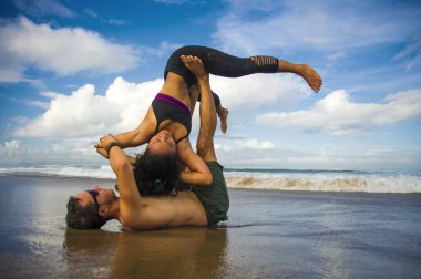 Genç çekici ve konsantre olmuş bir çift akro yoga dengesi ve meditasyon egzersizi yapan akrobat. Mavi bir gökyüzü altında zihin ve beden kontrolü.