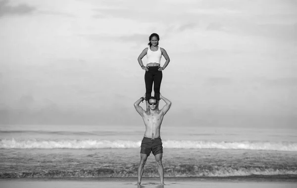 Ao ar livre estilo de vida retrato jovem atraente e concentrado casal de acrobatas de ioga praticando equilíbrio acroioga e exercício de meditação na bela praia — Fotografia de Stock