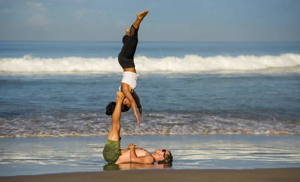 Genç çekici ve konsantre olmuş bir çift akro yoga dengesi ve meditasyon egzersizi yapan akrobat. Mavi bir gökyüzü altında zihin ve beden kontrolü. — Stok fotoğraf