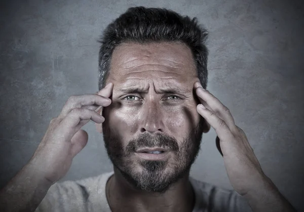 Close-up dramatisch portret van jonge aantrekkelijke angstige en depressieve man in pijn met handen op zijn hoofd lijden hoofdpijn en migraine en depressie crisis — Stockfoto