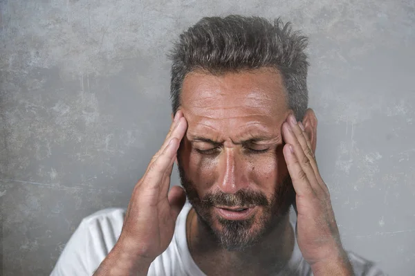 Close up retrato dramático de jovem atraente homem ansioso e deprimido com as mãos na cabeça sofrendo dor de cabeça e enxaqueca e depressão crise — Fotografia de Stock