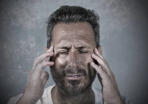 Nahaufnahme dramatisches Porträt eines jungen attraktiven ängstlichen und depressiven Mannes mit schmerzenden Händen auf dem Kopf, der unter Kopfschmerzen und Migräne und Depressionen leidet — Stockfoto