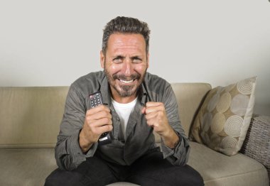 30'larında ya da 40'lı yaşlarında heyecanlı ve çekici bir adam evde spor maçı veya gerilim filmi izlerken eğleniyor televizyon oturma odasında ki kanepede otururken gergin hissediyorum