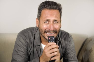 30'larında ya da 40'lı yaşlarında heyecanlı ve çekici bir adam evde spor maçı veya gerilim filmi izlerken eğleniyor televizyon oturma odasında ki kanepede otururken gergin hissediyorum