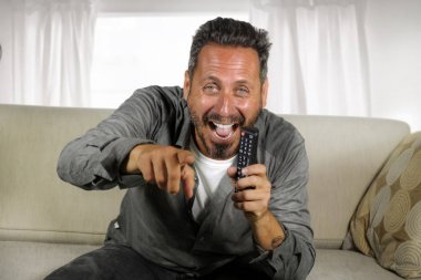 yakışıklı ve mutlu 30'lu ya da 40'lı yaşlar beyaz adam evde komik televizyon programı izlerken neşeli eğlenceli oturma rahat ve serin oturma oturma kanepe