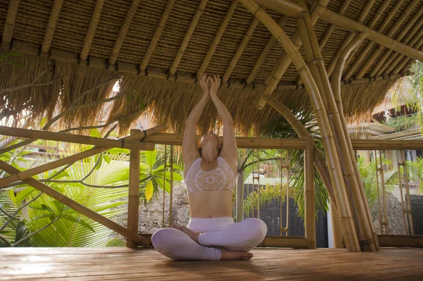 Junge attraktive und glücklich entspannte Frau sitzt in Lotus-Yoga-Position und macht Meditation und Konzentration im Freien in einer Holzhütte im wunderschönen tropischen Dschungel — Stockfoto