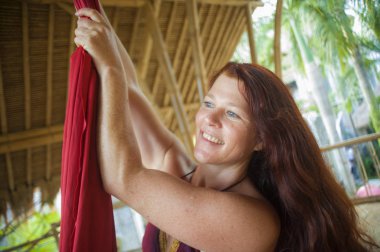 hava dans atölyesinde genç mutlu ve güzel kırmızı saçlı kadın portresi tropikal ahşap kulübeneşeli gülümseyerek ipek kumaş tutan aero dans öğrenme