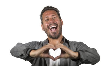 genç yakışıklı ve çekici mutlu adam elleri ve parmakları ile aşk kalp şekli işareti yapıyor portre stüdyo arka planda neşeli ve büyüleyici izole gülümseyen