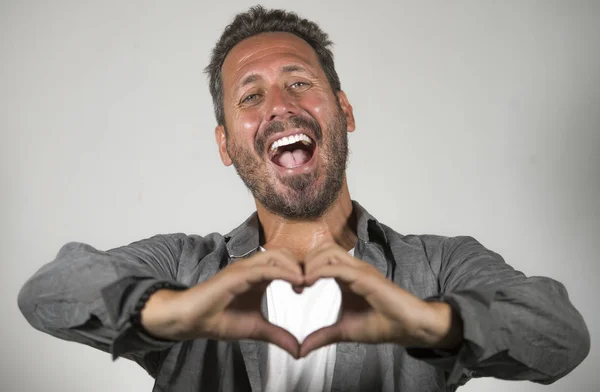 Retrato de joven guapo y atractivo feliz hombre haciendo amor corazón forma signo con las manos y los dedos sonriendo alegre y encantador aislado en el estudio de fondo — Foto de Stock