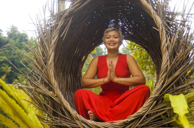 tropik ormanda yoga gevşeme ve meditasyon pratik şık ve güzel kırmızı elbise çekici ve mutlu 40s veya 50s orta yaşlı Asyalı kadın