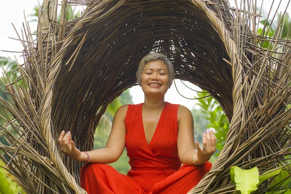 Atractiva y feliz mujer asiática de 40 o 50 años de edad en elegante y hermoso vestido rojo practicando yoga relajación y meditación en la selva tropical — Foto de Stock