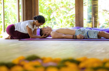 Genç, güzel ve egzotik Asyalı Taylandlı kadın geleneksel baş ve yüz masajı yapıyor. Alternatif tıp spa 'sında beyaz bir adama.