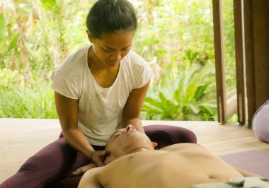 Genç, güzel ve egzotik Asyalı Taylandlı kadın. Geleneksel baş ve yüz masajı yapıyor. Beyaz bir adama.