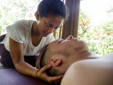 Genç, güzel ve egzotik Asyalı Taylandlı kadın. Geleneksel baş ve yüz masajı yapıyor. Beyaz bir adama.