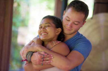 Genç, güzel ve egzotik Asyalı Balili kadın geleneksel sağlık spa bahçesinde yakışıklı beyaz bir masör tarafından Tayland masajı yaptırıyor. 