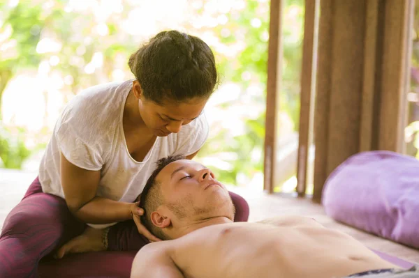 Joven hermoso y exótico asiático tailandés terapeuta mujer dando tradicional cabeza y facial balinés masaje a caucásico hombre en alternativa medicina curación spa —  Fotos de Stock