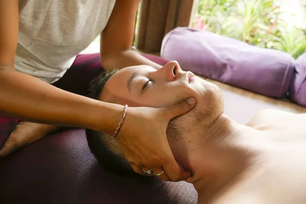 Joven hermoso y exótico asiático tailandés terapeuta mujer dando tradicional cabeza y facial balinés masaje a caucásico hombre en armonía salud cuidado y bienestar —  Fotos de Stock