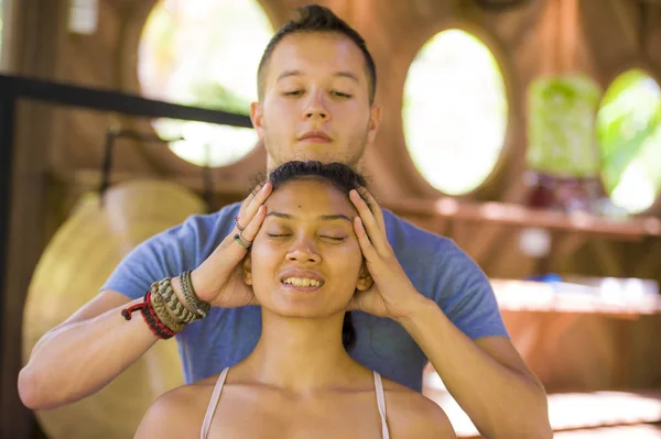 Retrato de estilo de vida natural de jovem bonita e relaxada asiática balinesa recebendo uma cura facial e cabeça massagem tailandesa por terapeuta masculino no spa tradicional — Fotografia de Stock