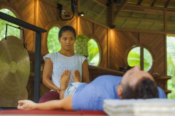 Jovem bonito e exótico asiático balinês wellness terapeuta dando corpo massagem tailandesa para atraente homem caucasiano no tradicional jardim spa em cuidados de saúde conceito de relaxamento — Fotografia de Stock