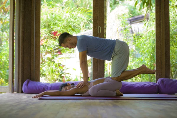 Junge schöne und exotische asiatische Balinesin erhält körperheilende thailändische Massage von attraktiven kaukasischen Masseur Mann im traditionellen Wellness-Kurpark — Stockfoto