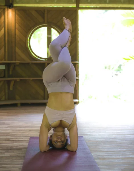 Genç ve sağlıklı Endonezyalı akrobat kadın akro yoga egzersizi yapıyor dengede durması için geleneksel stüdyo eğitiminde uyum içinde yoğunlaşmıştı. — Stok fotoğraf