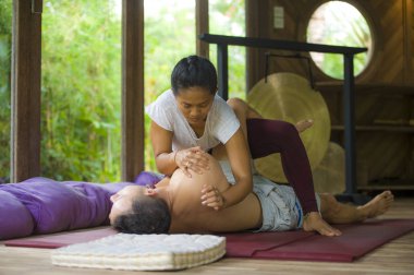 Genç, güzel ve egzotik Asyalı Endonezyalı kadın erkek için geleneksel Tayland masajı yapıyor. Tropikal sağlıklı yaşam tarzında rahatlamış.
