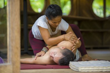 Genç, güzel ve egzotik Asyalı Endonezyalı kadın erkek için geleneksel Tayland masajı yapıyor. Tropikal sağlıklı yaşam tarzında rahatlamış.